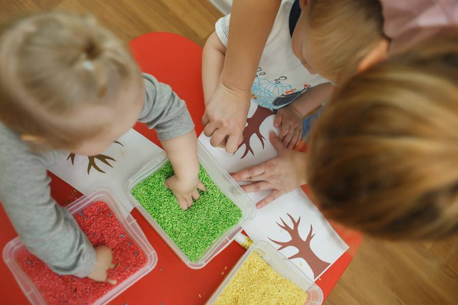 Children play educational games with a sensory bin in kindergarten.